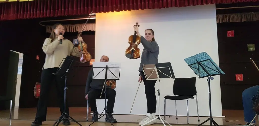 Eine Musikerin spricht ins Mikrofon, eine zweite hält eine Geige hoch