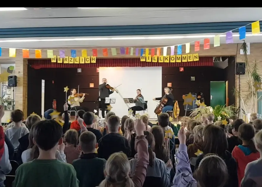 Kinder halten gebastelte Sterne hoch, während das Quartett auf der Bühne spielt