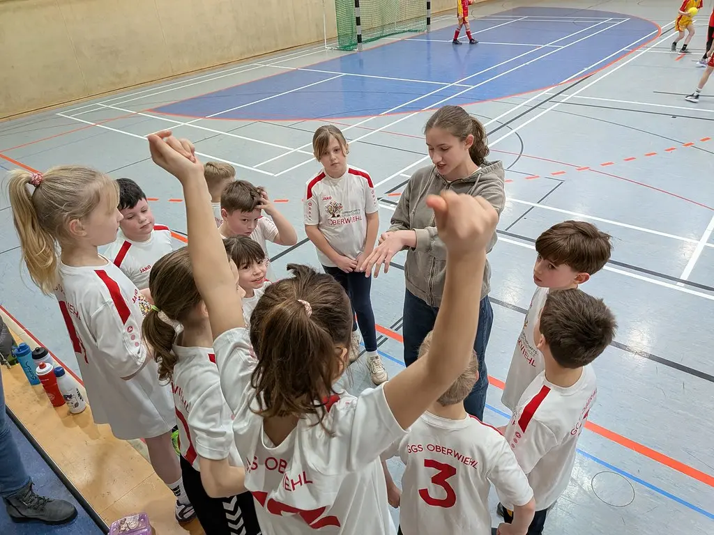 Mannschaftsbesprechung im Kreis in der Sporthalle, eine Betreuerin gibt Anweisungen