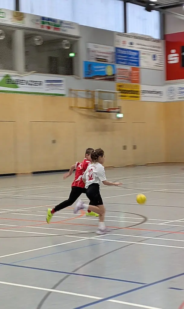 Zwei Kinder sprinten dem Ball hinterher über das Spielfeld