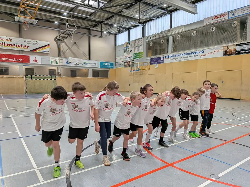 Die Mannschaft läuft in einer Reihe eingehakt über das Hallenfeld