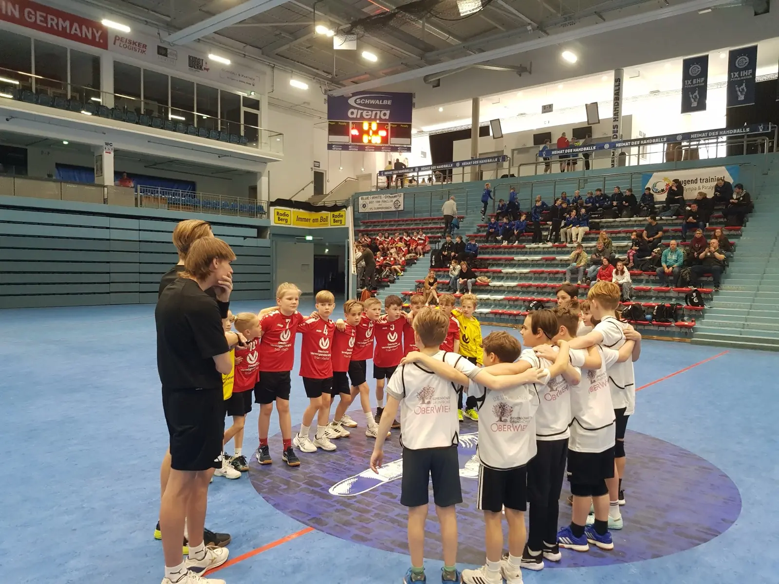 Zwei Kindermannschaften stehen im Kreis in einer Sporthalle vor dem Spiel