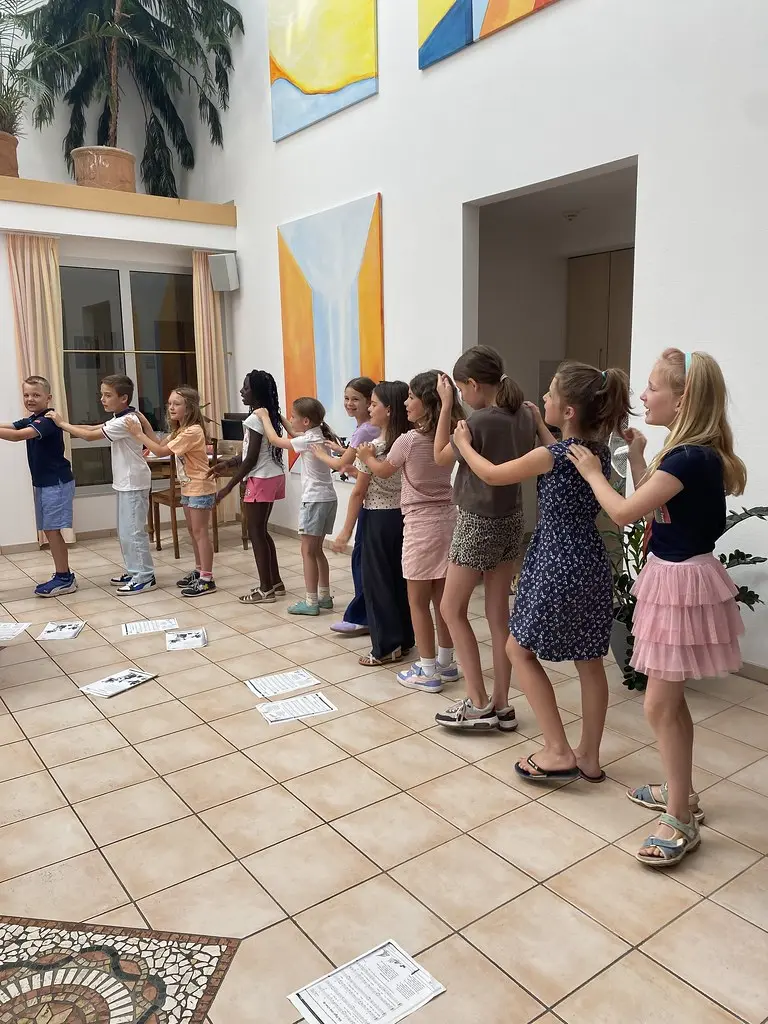 Kinder stehen hintereinander in einer langen Reihe und legen die Hände auf die Schultern der Vorderleute