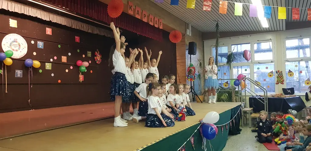 Eine Tanzgruppe in weißen Shirts und dunklen Glitzerröcken tanzt vor dem Publikum
