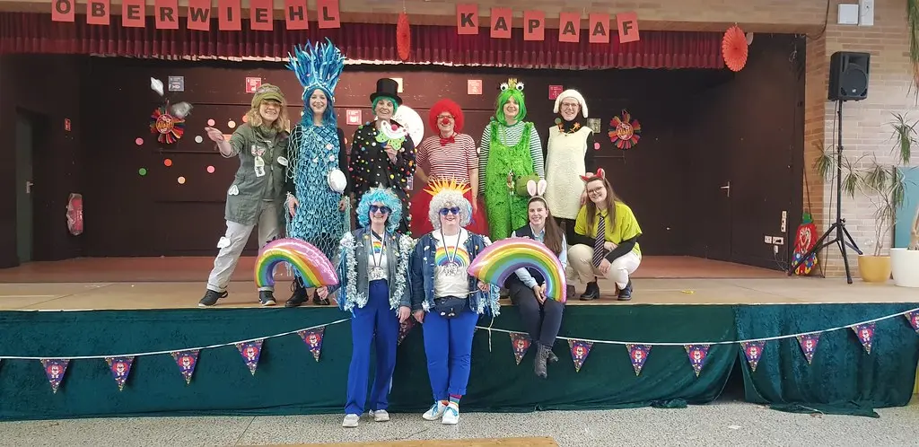 Gruppenbild des verkleideten Kollegiums auf der geschmückten Bühne in der Aula