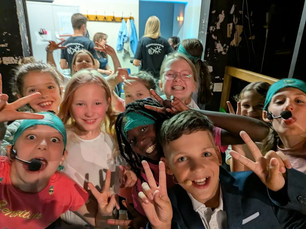 Eine Gruppe Kinder posiert hinter der Bühne lachend mit Peace-Zeichen