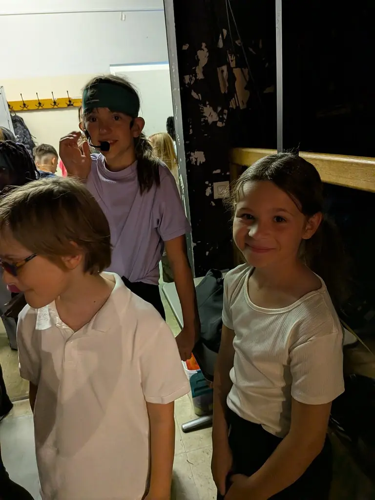 Drei Kinder stehen hinter der Bühne im Gang und warten auf ihren Auftritt