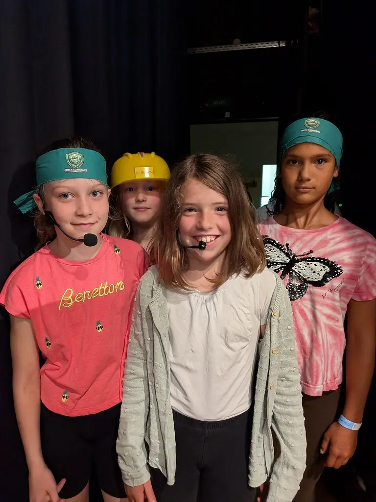 Vier Kinder mit „Green Guardians“-Stirnbändern und Headsets hinter der Bühne