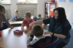Eine Betreuerin spielt gemeinsam mit mehreren Kindern an einem Tisch