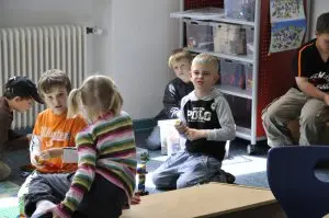 Mehrere Kinder sitzen zusammen auf dem Teppich der Spielecke
