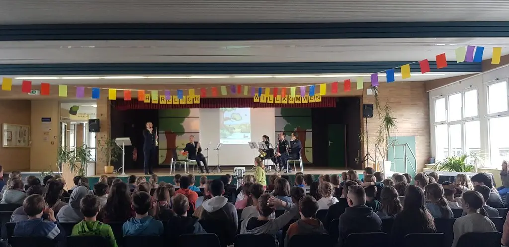 Viele Kinder sitzen in der Aula und verfolgen die Aufführung auf der Bühne