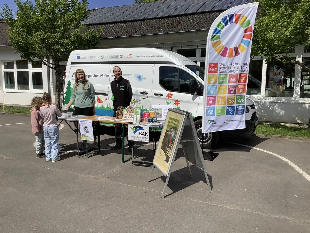 Kinder an einem Infostand vor dem Fahrzeug des Bergischen Naturmobils auf dem Schulhof