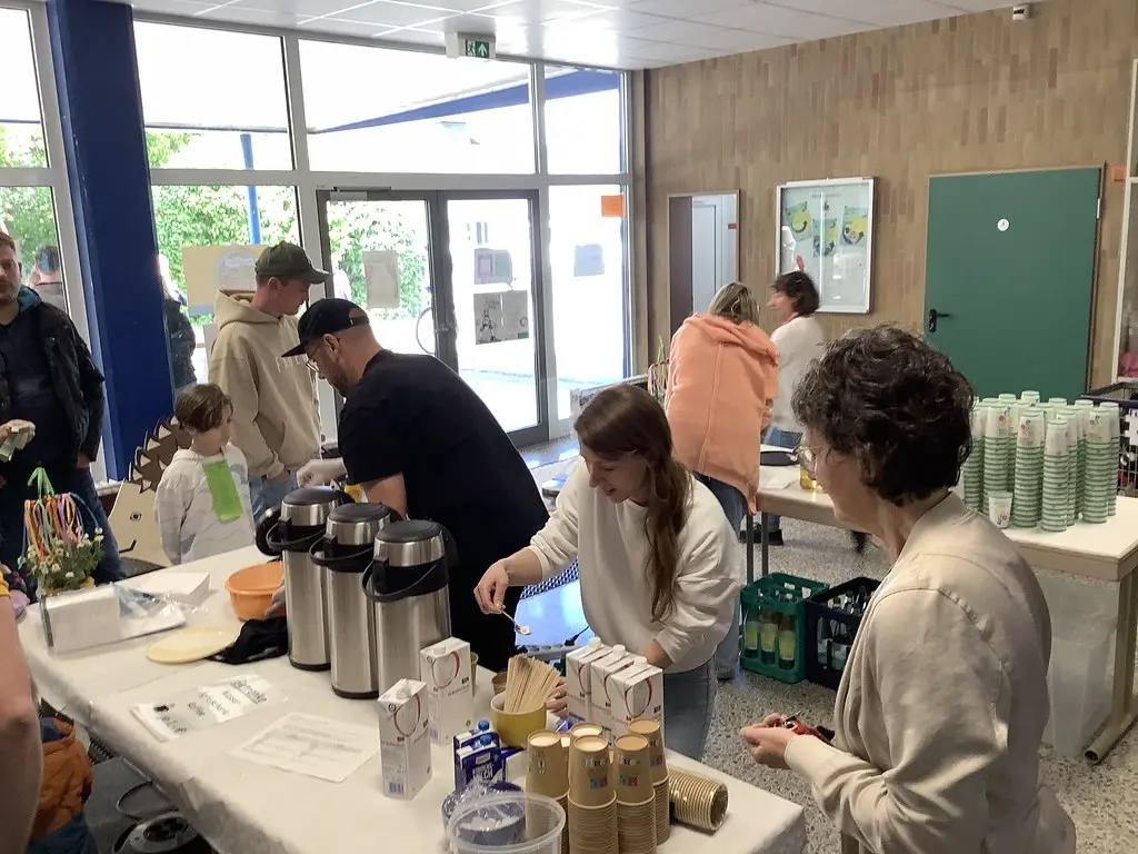 Erwachsene bereiten an Tischen in der Aula Getränke für Gäste vor