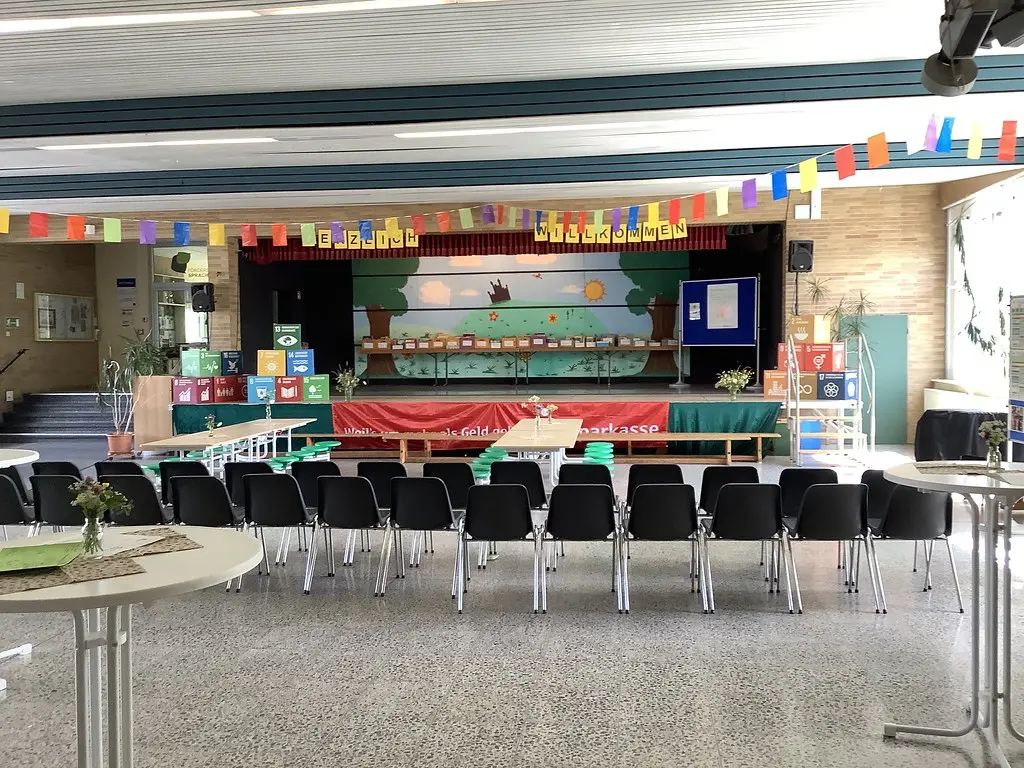 Aula mit Stuhlreihen, bunten Wimpelketten und geschmückter Bühne vor der Veranstaltung