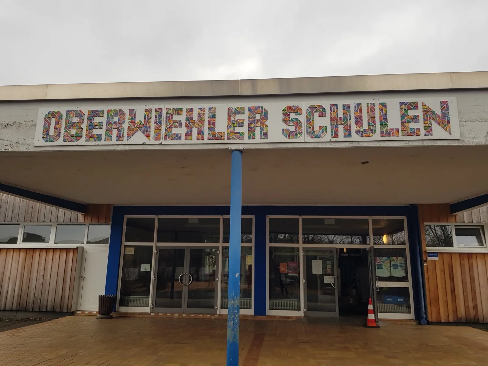 Haupteingang der Oberwiehler Schulen mit bunt gestaltetem Schriftzug über den Glastüren