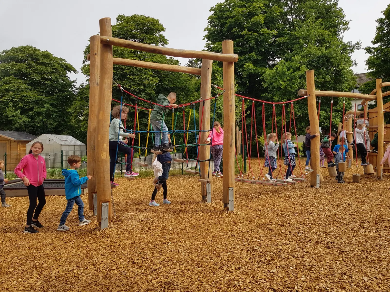 Mehrere Kinder klettern und balancieren auf dem Kletterparcours des Schulhofs