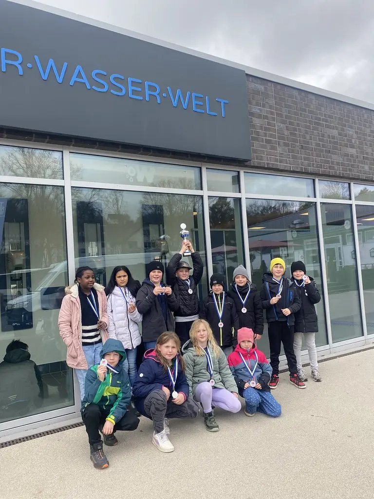 Kindergruppe mit Medaillen und Pokal unter dem Schriftzug der Wiehler Wasser-Welt