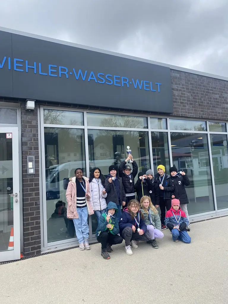Kinder halten ihre Medaillen hoch, ein Pokal wird in die Luft gestreckt